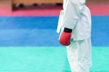 Sports background concept for martial arts with shallow depth of field and motion blur effect. An athlete in a white kimano with a red belt on the tatami before the fight.