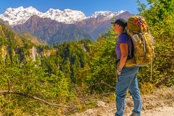 Fototapeta na wymiar Female Trekker with large backpack looking at view on the Annapurna Circuit Trek on a sunny cloudless day