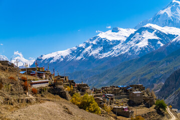Small high altitude village with snowy Annapurna mountain range in the distance, Nepal - obrazy, fototapety, plakaty