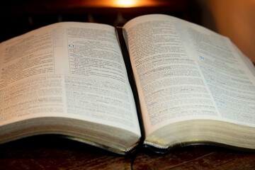 Holy Bible open on a wooden table with its sides slightly folded down