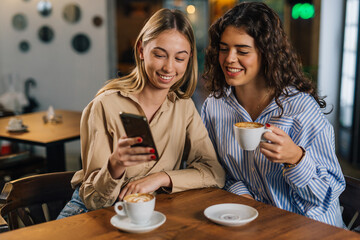 Two women looking at phone in a cafe