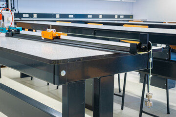 A small cart on a rail is connected with a string to falling weights over a pulley. A time ticker registers the movement of the cart in time. Experiment in physics class.