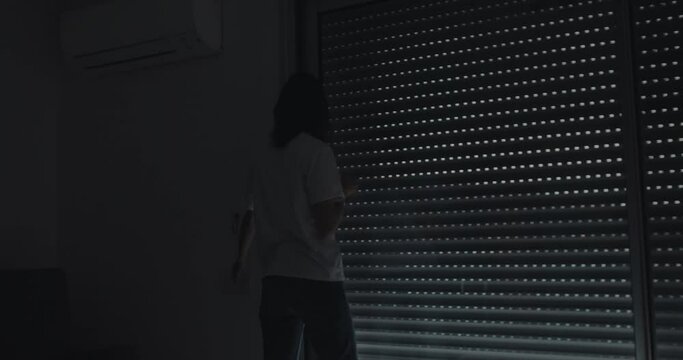 Woman in living room enjoying coffee in morning while automatic roller shutter open the window