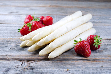 Reife rote Erdbeeren und weißer Spargel aus biologischem Anbau angeboten als close-up auf einem...