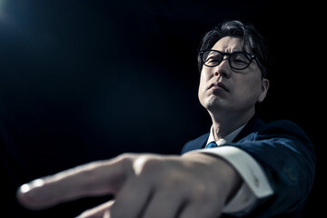 Obraz premium 指を差して偉そうに指示をしているビジネスマンのミドル男性