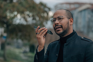 latin man talking on mobile phone with hands free or sending voice message