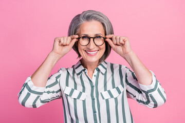 Portrait photo of old pensioner business lady cheerful smile touch her glasses good vision after correction isolated on pastel pink color background