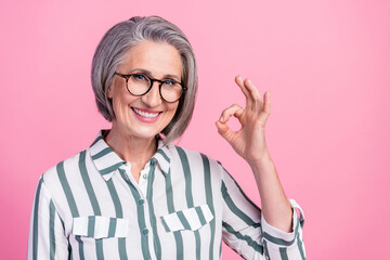 Photo of cute charming lady wear smart casual clothes smiling showing okey gesture isolated pink color background