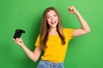 Photo of young overjoyed schoolgirl teenager wear orange t-shirt fists up hooray hold joystick win...