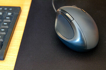 Ergonomiczna myszka komputerowa na czarnej podkładce na biurku