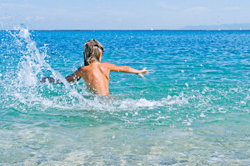 girl from the back  splashes into the sea