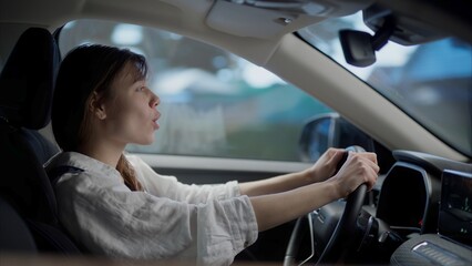 Caucasian female dancing and singing to her favorite song while driving the car during the suburbs...
