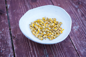 Dry herbal tea from Great mullein flowers or Verbascum thapsus in a small clay bowl on wood background. 