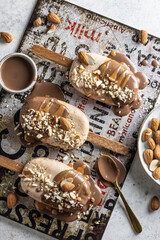 A few delicious homemade vegan ice cream bars or popsicles covered with chocolate and nuts top view, flat lay