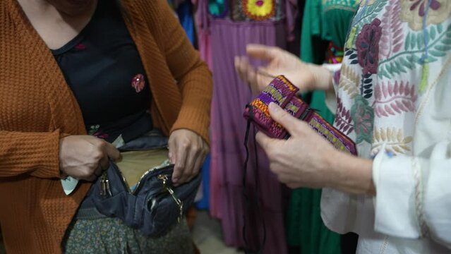 Mature woman exchanging Mexican pesos for a locally made souvenir purse that she is buying in a shop in Yucatan, Mexico.