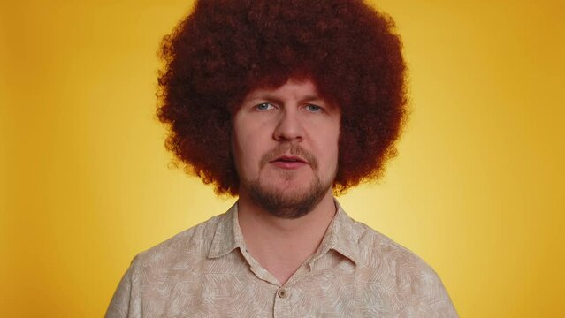 What Why. Sincere irritated man with lush afro hairstyle raising hands in indignant expression asking reason of failure demonstrating disbelief irritation by trouble. Confused guy on yellow background