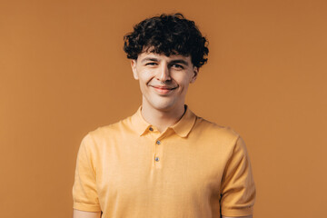 Handsome man in yellow wear on studio background. Curly haired guy looking to camera. Cheerful...