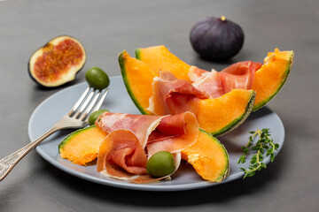 Green olives on a fork, jamon on a slice of melon