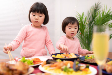 テーブルに並べられたクリスマスの料理を食べる子供