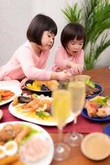 テーブルに並べられたクリスマスの料理を食べる子供