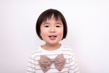 白い壁の前で笑っている3歳の女の子