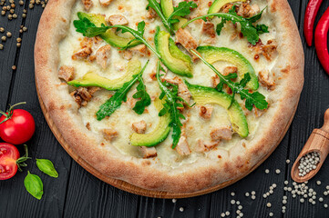 Delicious pizza with grilled chicken, avocado, and arugula.