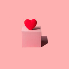 Red heart and light pink cube on pastel background. Modern Valentine's Day concept. Creative love idea. Minimalistic Mother's Day composition.