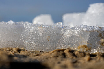 Zbliżenie na kawałek lodu leżący na piasku  na zamarzniętym jeziorze.