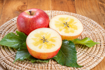 Honey apple on wooden mat over wooden background table, Sweet honey core apple fruit on wooden background.
