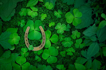 horseshoe for good luck and clover leaves on natural green forest background. symbol of irish traditional holiday St. Patrick’s Day. top view. copy space. template for design