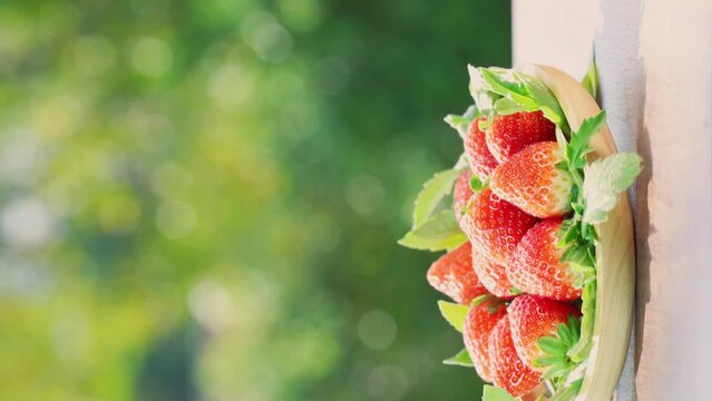 Fresh strawberries in wooden basket on green bokeh background,  Red strawberries Pine berry or Hula strawberry on nature background.