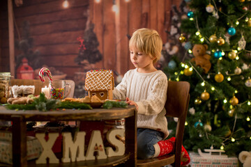 Blond toddler child, cute boy, making Christmas ginger bread house
