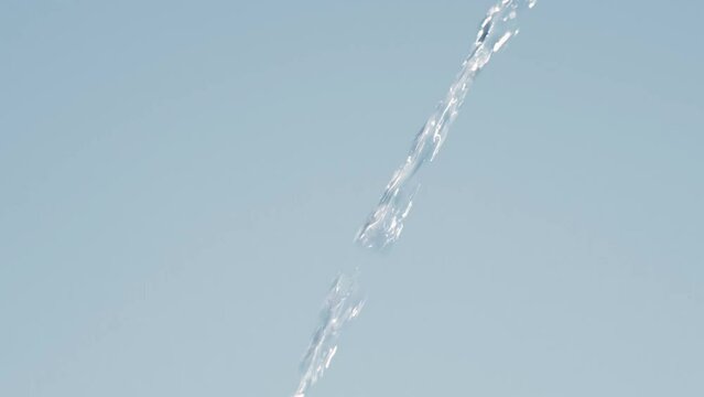 Beautiful pure Water jet flow in slow motion on blue background. Full HD slow motion video of water flowing from top to bottom.