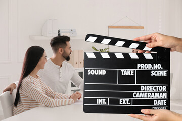 Shooting movie. Second assistant camera holding clapperboard in front of actors at film set