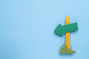 Paper signpost with arrow on light blue background, top view. Space for text