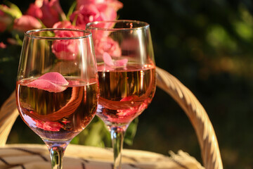 Glasses of delicious rose wine with petals outside. Space for text