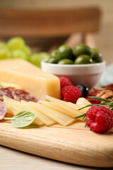 Snack set with delicious Parmesan cheese on wooden board, closeup