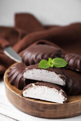 Delicious chocolate covered marshmallows with mint on white wooden table, closeup