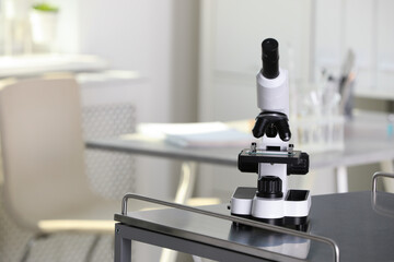 Modern medical microscope on metal table in laboratory, space for text