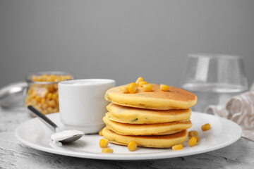 Tasty corn pancakes with sweet kernels and sauce served on grey table, closeup