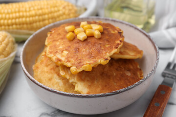 Tasty corn pancakes in bowl on table, closeup
