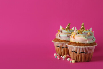 Cute sweet unicorn cupcakes on pink background, space for text