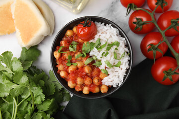 Delicious chickpea curry in bowl on white marble table, flat lay