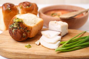 Delicious pampushky (buns with garlic), green onions and salo served for borsch on table, closeup. Traditional Ukrainian cuisine