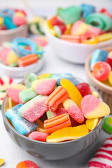 Bowl of tasty colorful jelly candies on white table, closeup