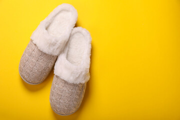 Pair of beautiful soft slippers on yellow background, top view