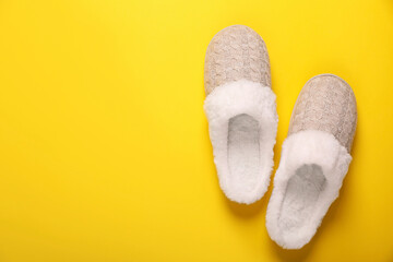 Pair of beautiful soft slippers on yellow background, top view. Space for text