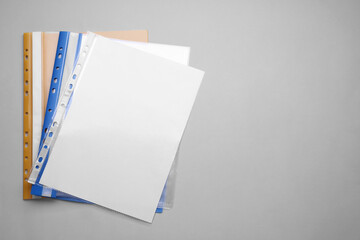 File folders with punched pockets and paper sheets on light grey background, flat lay. Space for...
