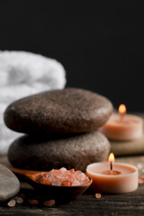 Fototapeta na wymiar Beautiful composition with spa stones and burning candles on wooden table, closeup