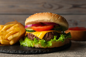 Delicious burger and french fries served on grey table, closeup